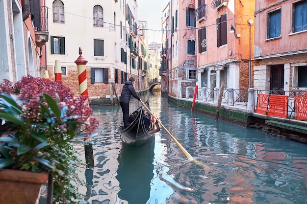 O gondoleiro de Veneza Itália anda de gôndola pelo estreito canal entre casas coloridas