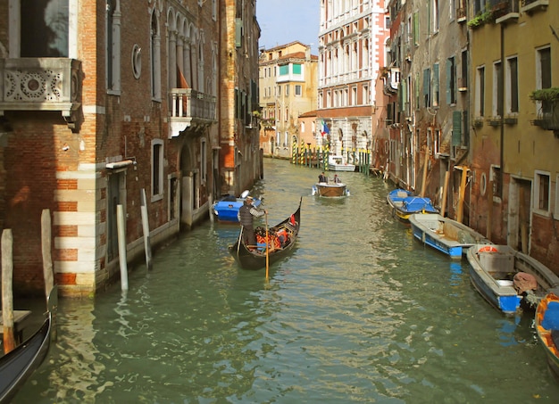 O gondoleiro navegando uma gôndola em um pequeno canal de Veneza, Itália