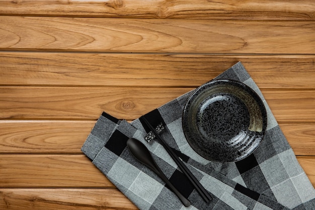 O grés repousa sobre uma toalha de mesa quadriculada preta na mesa de madeira