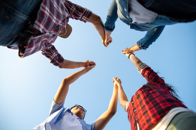 O grupo de amigos felizes levantou os braços junto, felicidade da amizade, conceito da parceria.