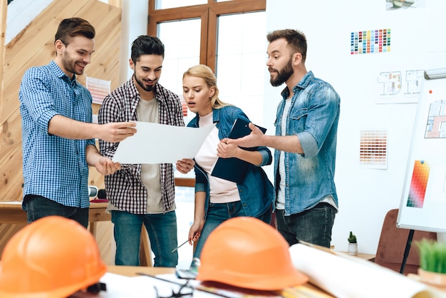 O grupo de arquitetos dos desenhistas olha o modelo.