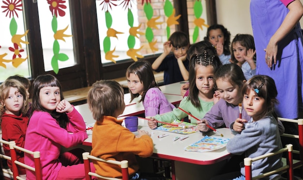 o grupo de crianças felizes se diverte e brinca no conceito de educação pré-escolar interna do jardim de infância com o professor