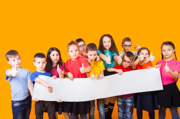 O grupo de crianças segurando um grande cartaz de espaço de cópia em branco