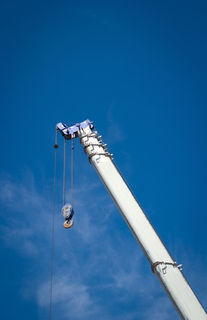 O guindaste de construção para levantamento pesado contra um céu azul de volta