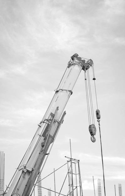 O guindaste de construção para levantamento pesado contra um céu azul de volta