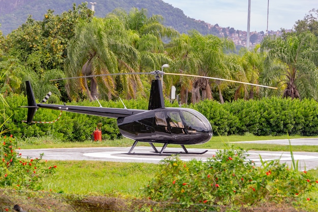 O helicóptero preto modelo R44 raven ll parou no heliporto da lagoa rodrigo de freitas, no rio de janeiro.