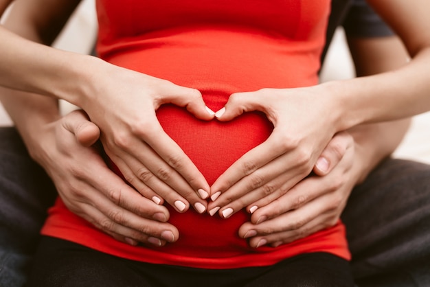 O homem abraça a barriga da esposa grávida.