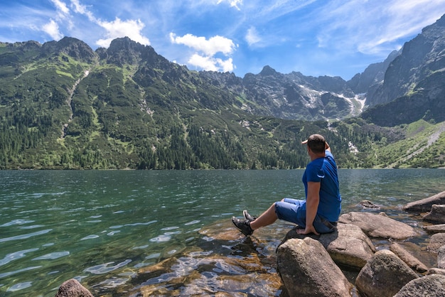 O homem admira a paisagem montanhosa no lago