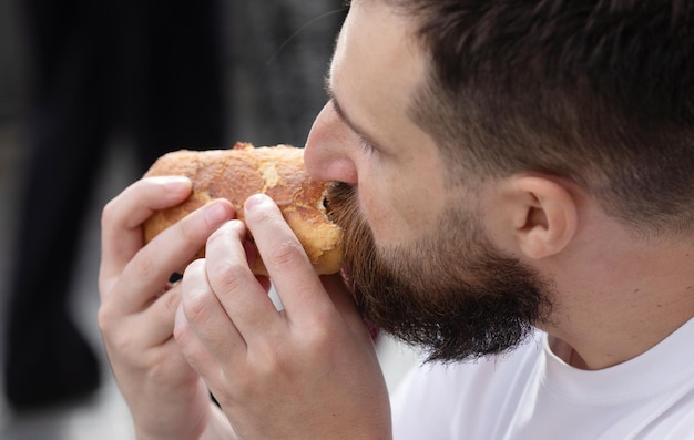 O homem almoça. Ele está olhando para seu sanduíche e comê-lo imediatamente.