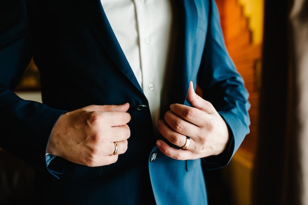 Foto o homem aperta os botões o noivo em uma camisa de terno em pé na sala close-up