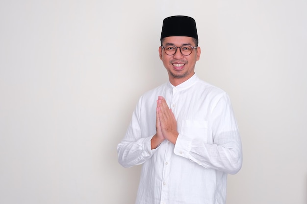 Foto o homem asiático muçulmano faz uma saudação amigável com a mão orando
