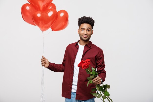 O homem atrativo novo que prende o balão vermelho e levantou-se para surprising sua amiga.