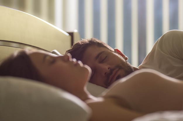 Foto o homem bonito dormindo perto de uma mulher na cama