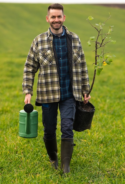 O homem bonito vai plantar uma árvore no campo