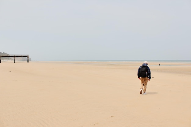 O homem caminhando na praia na Normandia