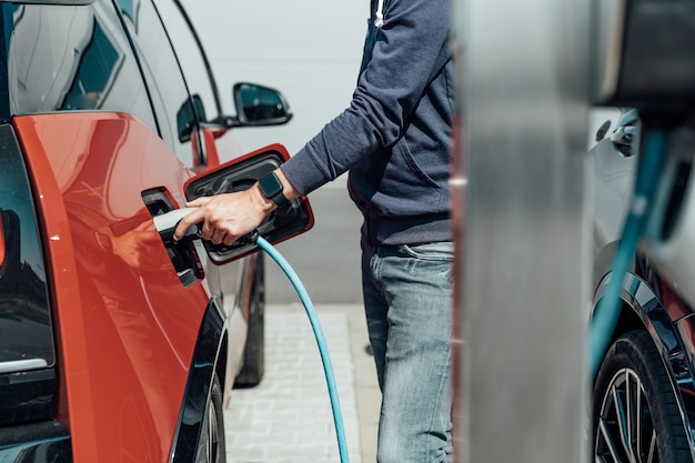 O homem carrega o carro elétrico na estação de carregamento