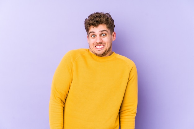 O homem caucasiano do cabelo encaracolado louro novo isolado funde as bochechas, tem expressão cansada. conceito de expressão facial.