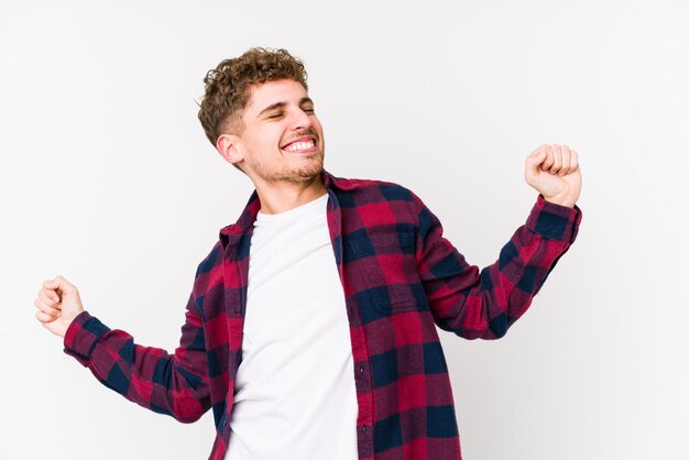 O homem caucasiano do cabelo encaracolado louro novo isolou esticando os braços, posição relaxada.