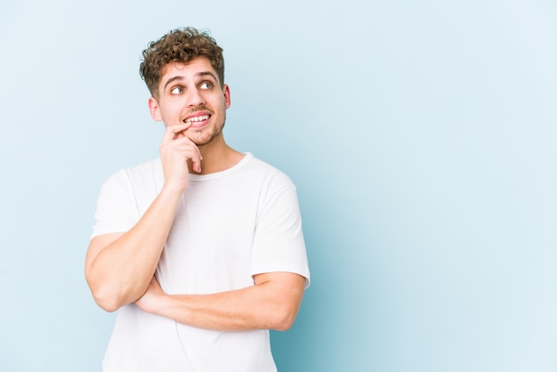 O homem caucasiano do cabelo encaracolado louro novo isolou o pensamento relaxado sobre algo que olha um espaço da cópia.