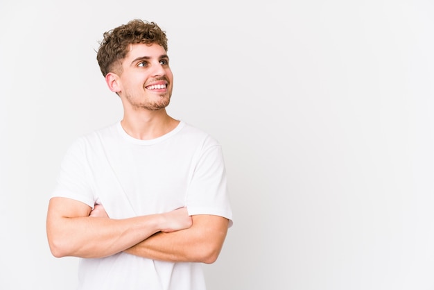 O homem caucasiano do cabelo encaracolado louro novo isolou o sorriso seguro com braços cruzados.