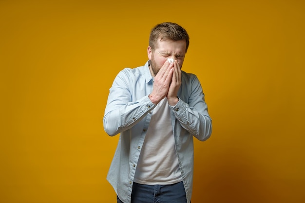 O homem caucasiano está doente tem um nariz escorrendo ele tosse ou espirra cobrindo a boca com um lenço