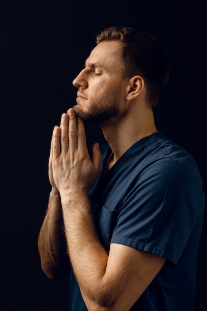 O homem cobre o rosto com as mãos e pensa na vida. Homem bonito orar e acreditar em Deus. Fé cristã ortodoxa.