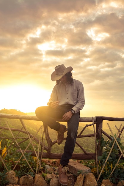 O homem com o chapéu de cowboy ao anoitecer