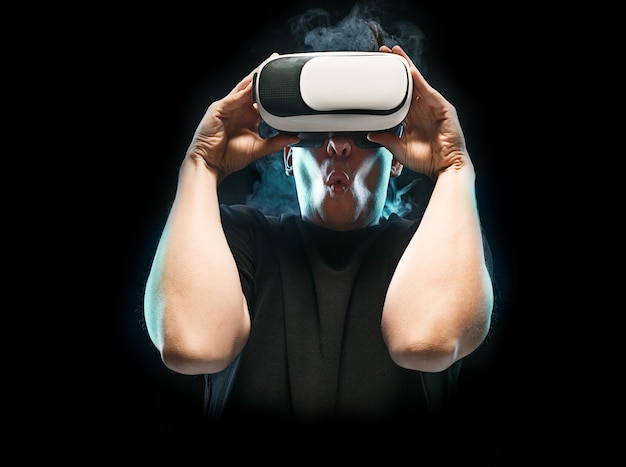 O homem com óculos de realidade virtual. Conceito de tecnologia do futuro. Fundo preto esfumaçado de estúdio