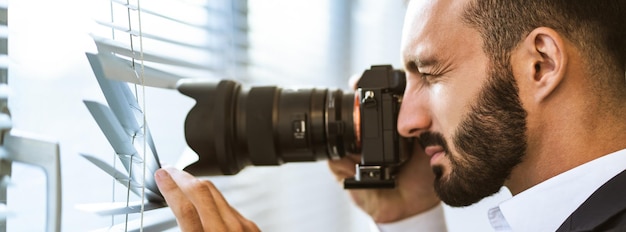 Foto o homem com uma câmera fotografando através das cortinas