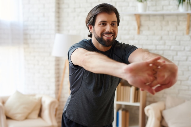 O homem considerável que faz esticando os dedos exercita em casa.