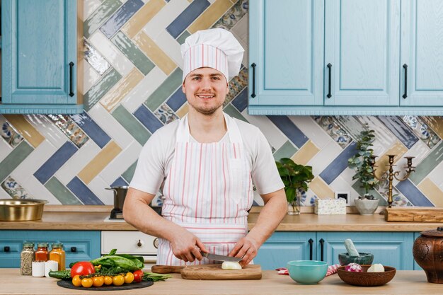 O homem corta uma cebola branca com uma faca. O conceito de cozinhar.