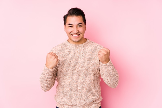 O homem curvilíneo novo que levanta em uma parede cor-de-rosa isolou torcendo despreocupado e entusiasmado. conceito de vitória