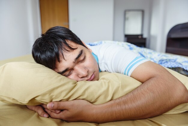 O homem de ásia dormindo na cama.