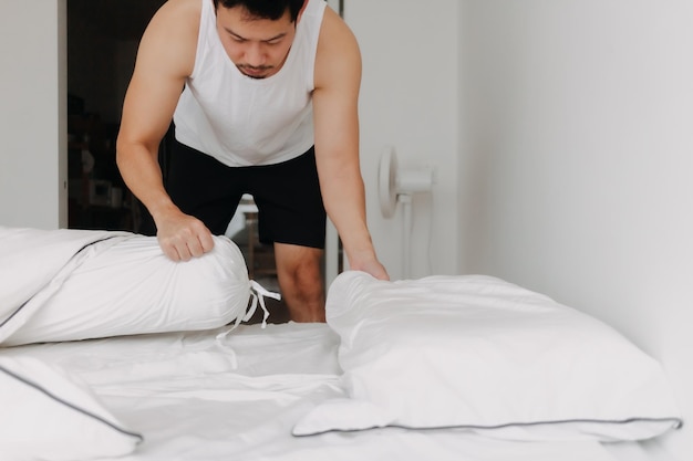 O homem de blusa branca está fazendo a cama dobrar em um sofá