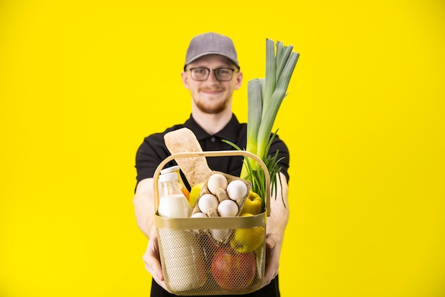 O homem de entrega de sorriso guarda a cesta com mantimentos, foco na cesta