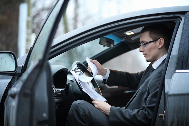 o homem de fato de negócios está sentado no carro