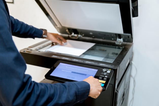 O homem de negócio entregue o botão da imprensa no painel da impressora, fontes da máquina da cópia do escritório do laser do varredor da impressora começam o conceito.