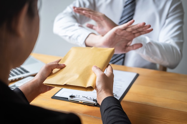 O homem de negócio que recusa e não recebe a cédula do dinheiro na oferta do envelope das pessoas fêmeas