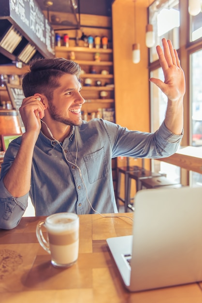 O homem de negócios considerável nos fones de ouvido está usando um portátil.