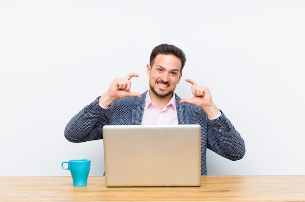 O homem de negócios considerável novo que molda ou que descreve o próprio sorriso com ambas as mãos que olham o conceito positivo e feliz do bem-estar