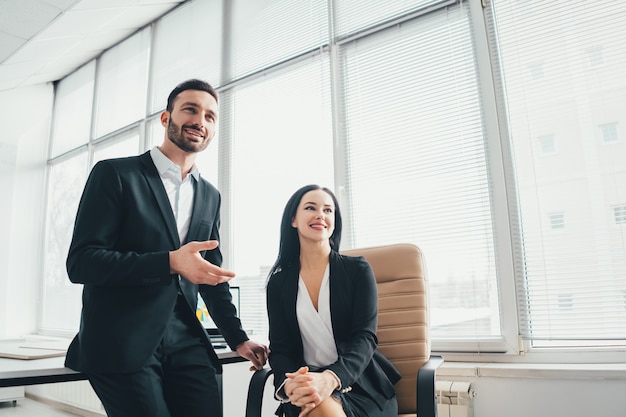 O homem de negócios e uma mulher conversando perto da mesa do escritório