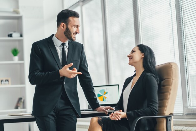 O homem de negócios e uma mulher conversando perto da mesa do escritório