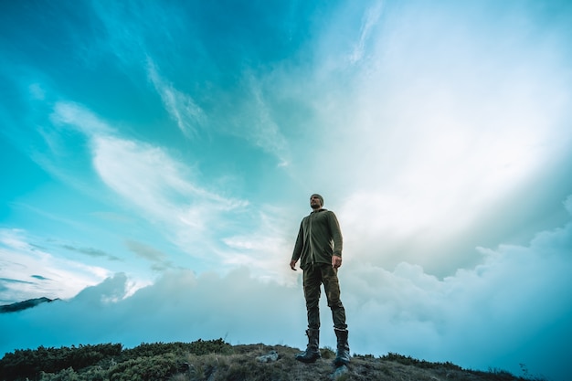 O homem de pé na montanha em um fundo de belas nuvens