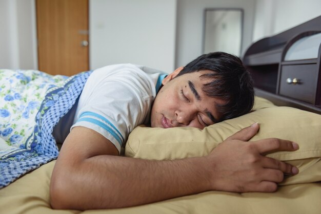 O homem de Ásia dormindo na cama.