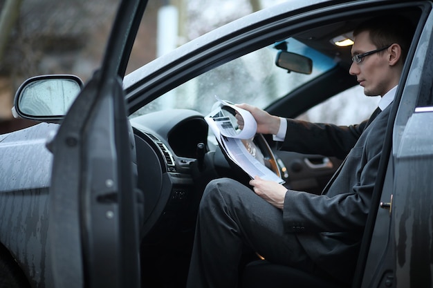 O homem de terno está sentado no carro