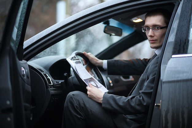 O homem de terno está sentado no carro