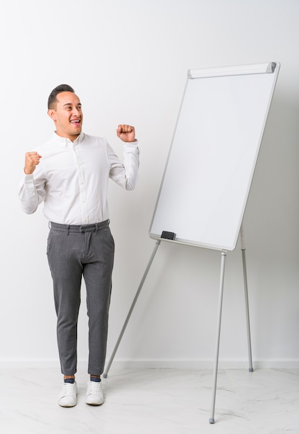 O homem de treinamento latin novo com um whiteboard isolou o levantamento do punho após uma vitória, conceito do vencedor.