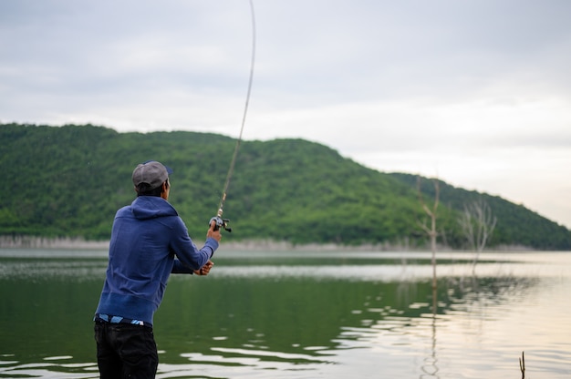 O homem de um pescador está pescando em um lago natural