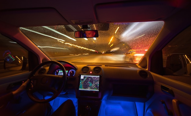 O homem dirige com um mapa na estrada das chuvas. noite à noite. vista interior