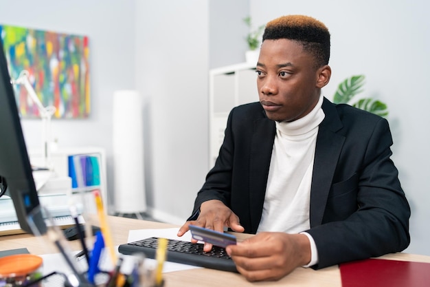 O homem do departamento de vendas do trabalhador de escritório senta-se à mesa em frente ao equipamento de bens necessários ao pedido do computador